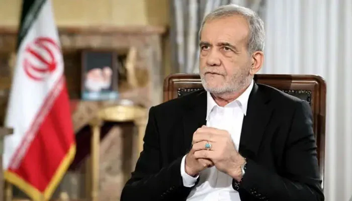 ایرانی صدر مسعود پزشکیان ایک پریس کانفرنس یا انٹرویو کے دوران سنجیدہ انداز میں بیٹھے ہوئے، پس منظر میں ایرانی پرچم واضح ہے۔