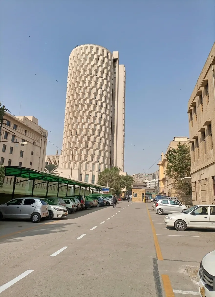 The iconic Habib Bank Plaza building on II Chundrigar Road Karachi under a clear day sky with a street view parking area