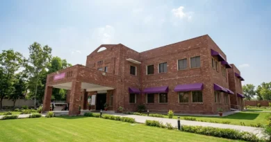 Front view of a newly constructed red brick THQ hospital building in Lahore with green lawns under a clear sky.