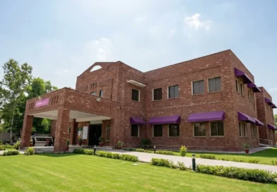 Front view of a newly constructed red brick THQ hospital building in Lahore with green lawns under a clear sky.