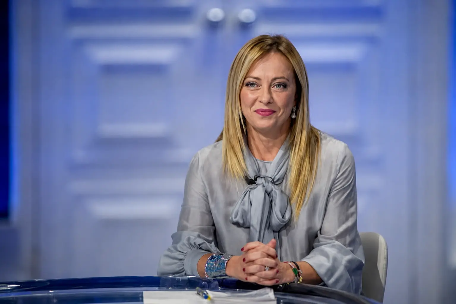 Italian Prime Minister Giorgia Meloni sitting confidently, representing her record-breaking long-term government.