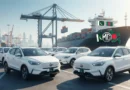 White MG cars parked at a port ready for export from Pakistan to Bangladesh with a cargo ship in the background.